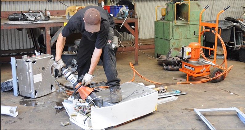 Holmatro handheld shear cutting an appliance in a scrap yard