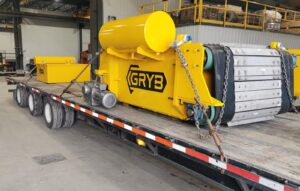 Yellow GRYB overband cross belt magnet on a flatbed trailer