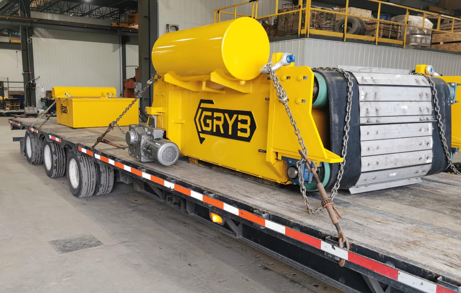Yellow overband cross belt magnet on a flatbed trailer